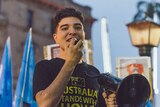 Drew Pavlou speaks into a megaphone at a protest at the University of Queensland.