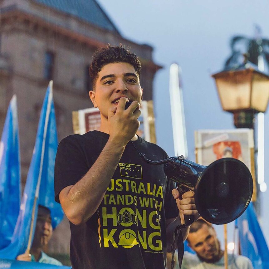Drew Pavlou speaks into a megaphone at a protest at the University of Queensland.
