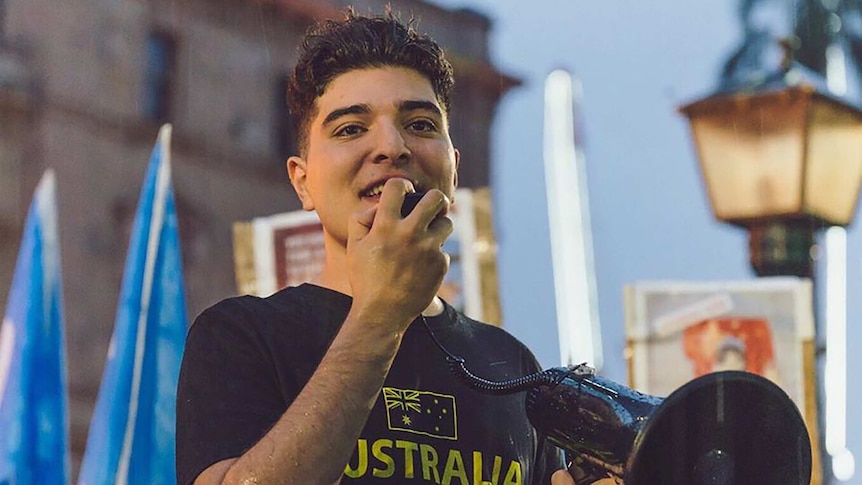 Drew Pavlou speaks into a megaphone at a protest at the University of Queensland.