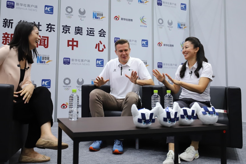 World Anti-Doping president Witold Banka and vice president Yang Yang hold up their hands as they speak to an interviewer.