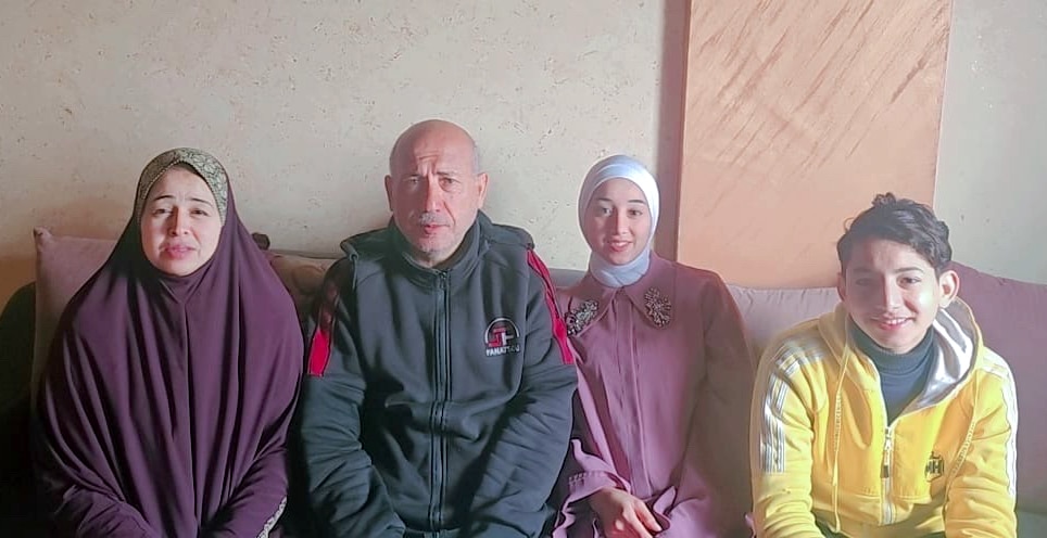 A family of four pose for a photo while sitting on a couch.