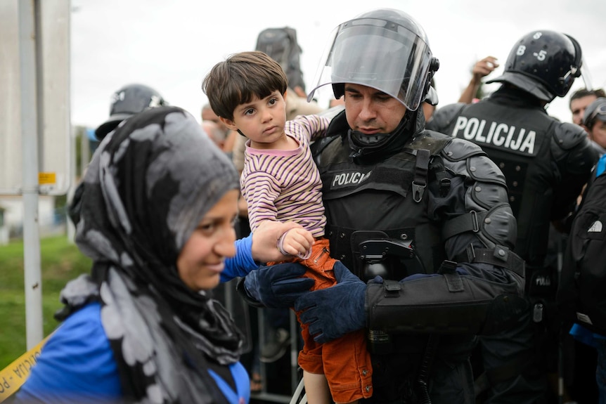 Police officer carries boy from border crossing