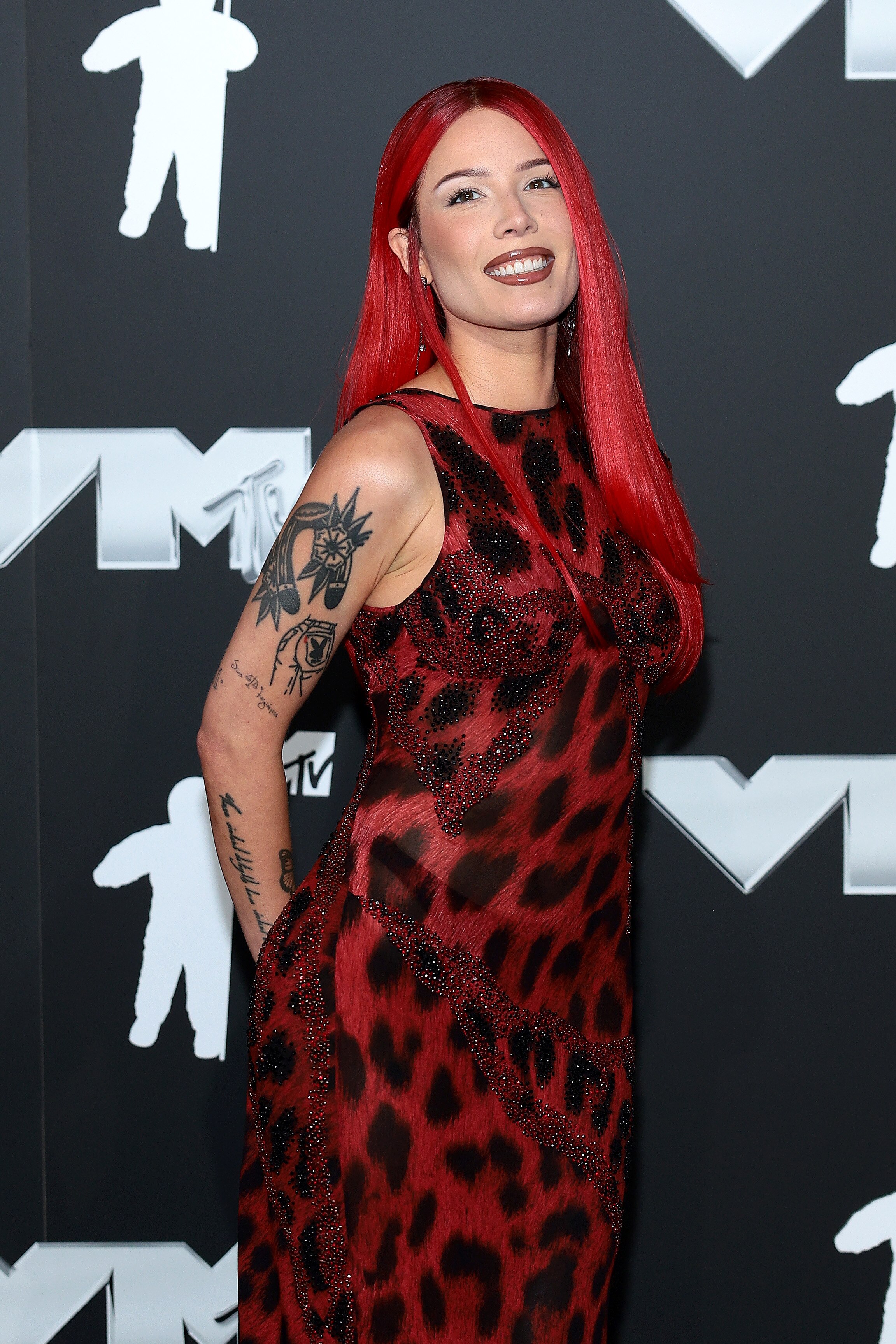 Halsey on the red carpet wearing a red cheetah print dress and has red hair