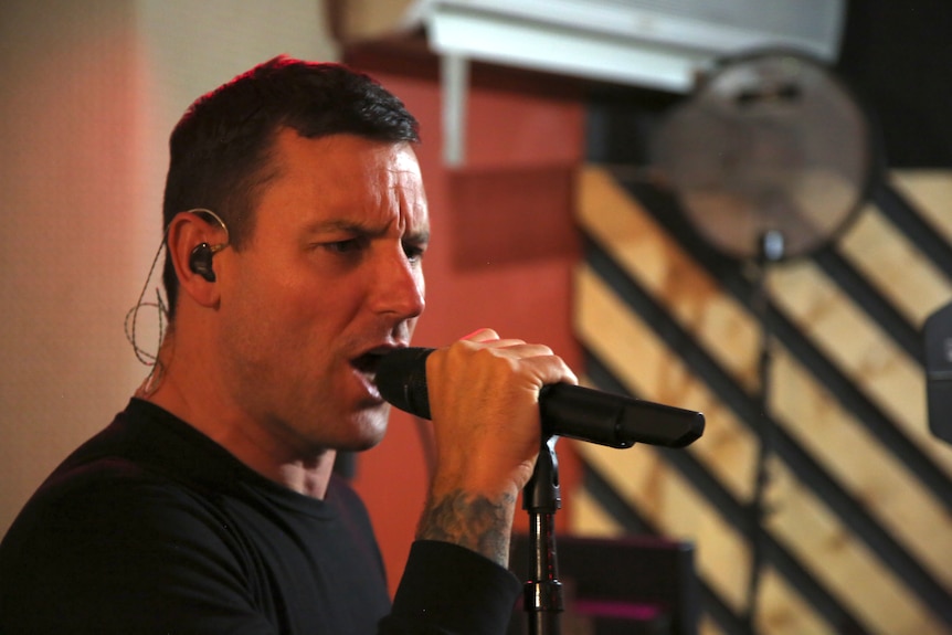 A close up of a man screaming into a microphone