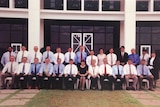 A class photo style of a group of mostly men, formed in two rows.