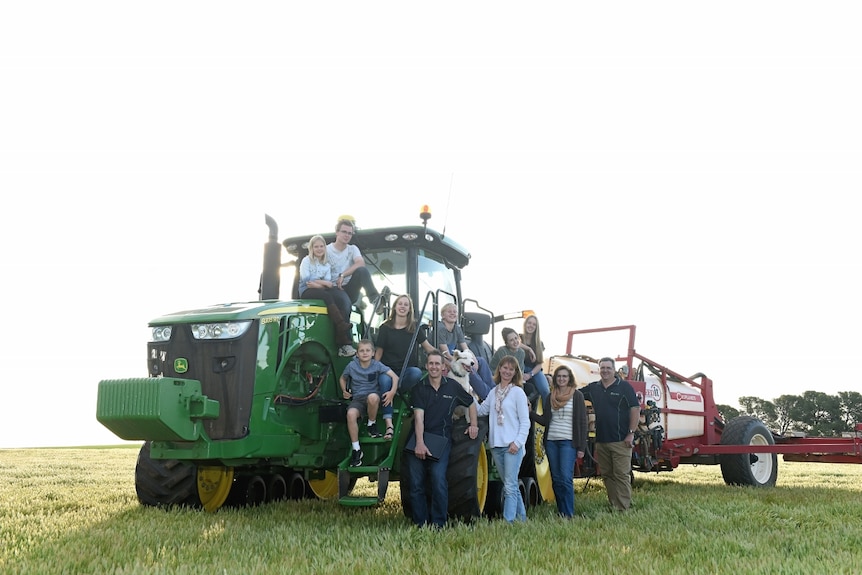 Two families sitting on a tractor.