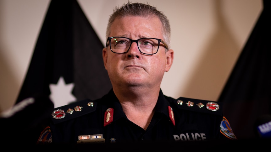 NT Police Commissioner Jamie Chalker standing at a lectern and looking up and to the side with a serious expression.