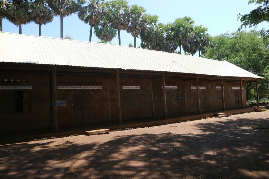 A school building stands amongst trees with a corrugated new roof