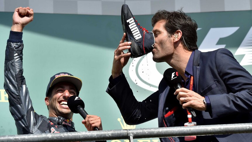 A man drinks champagne from a shoe as another man watches on in the background.