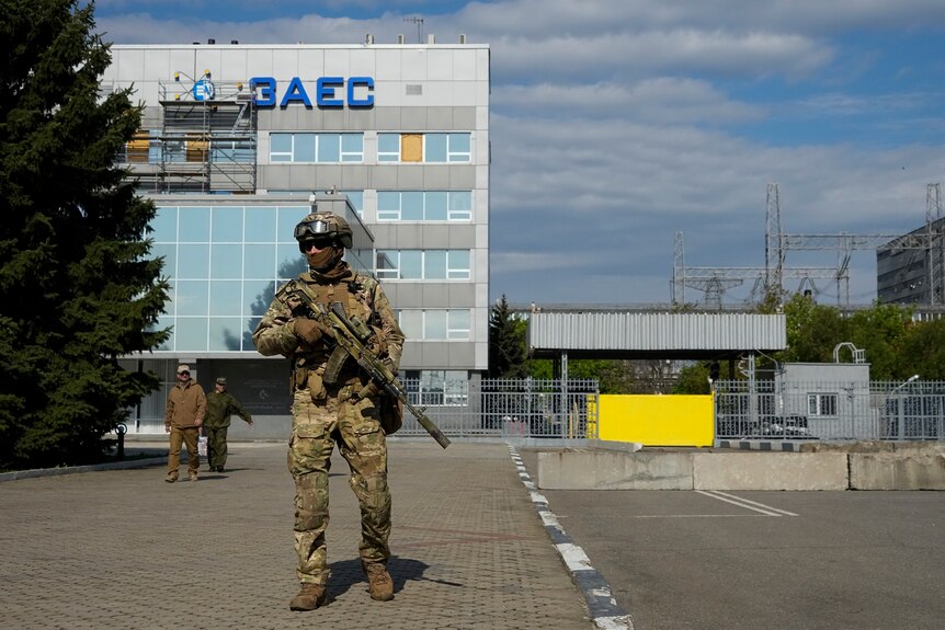 Russian serviceman stands guard outside of nuclear power plant building.
