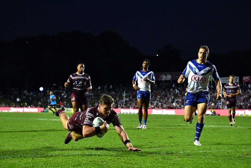 Reuben Garrick dives over the try line with the ball carried in his right arm as he scores for Manly against Canterbury.