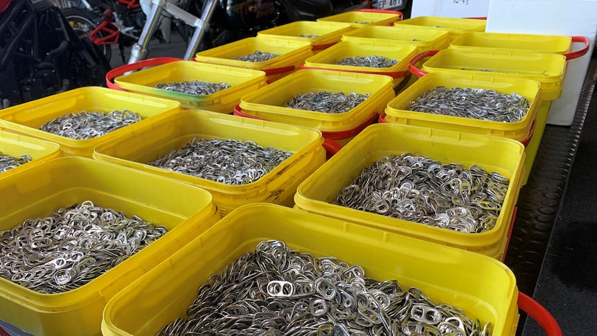 Around 18 yellow buckets and a large styrofoam box full of drink can ring-pulls.