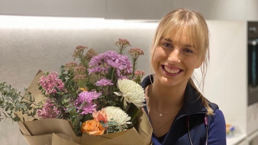 A nurse smiling with a bunch of flowers