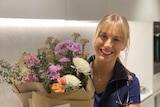 A nurse smiling with a bunch of flowers