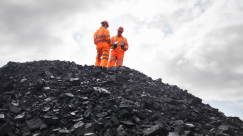 Coal miners stand on a pile of coal