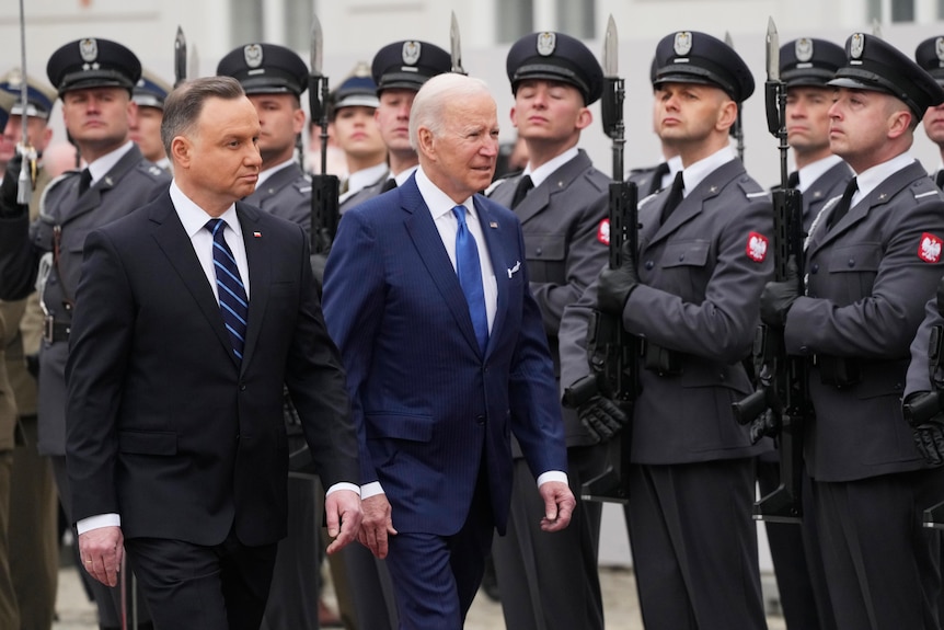 US President Joe Biden, centre, and Polish President Andrzej Duda walk past honour guard during a military welcome ceremony.