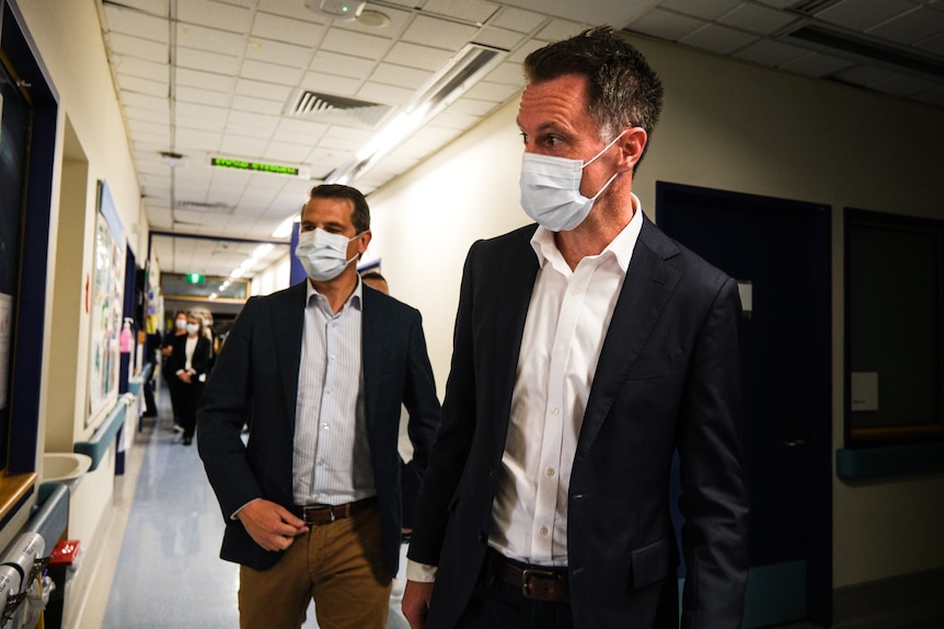 two men wearing masks inside a hospital