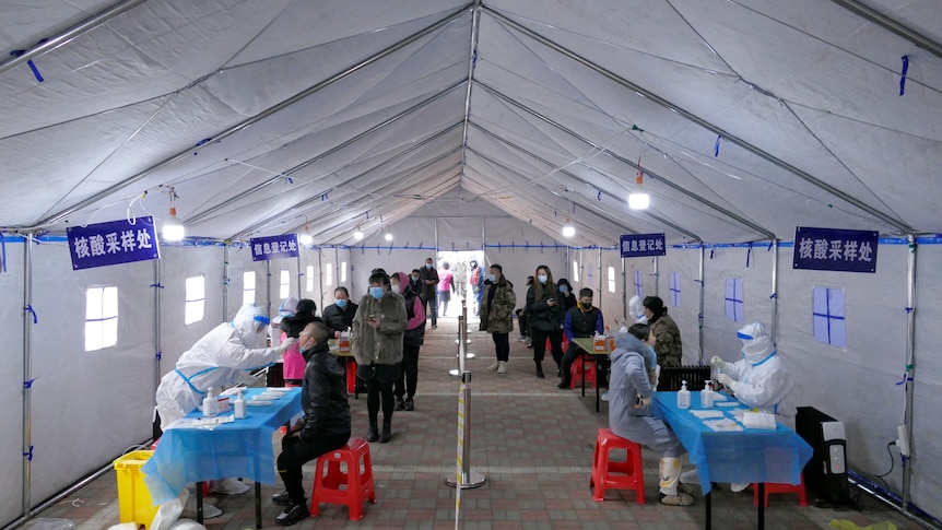 People line up in masks and PPE for the mass testing drive in Tianjin, January 9, 2022.