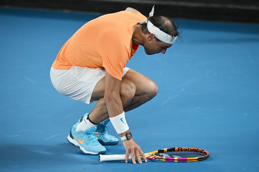Rafael Nadal bends over holding his racquet as he struggles with an injury.