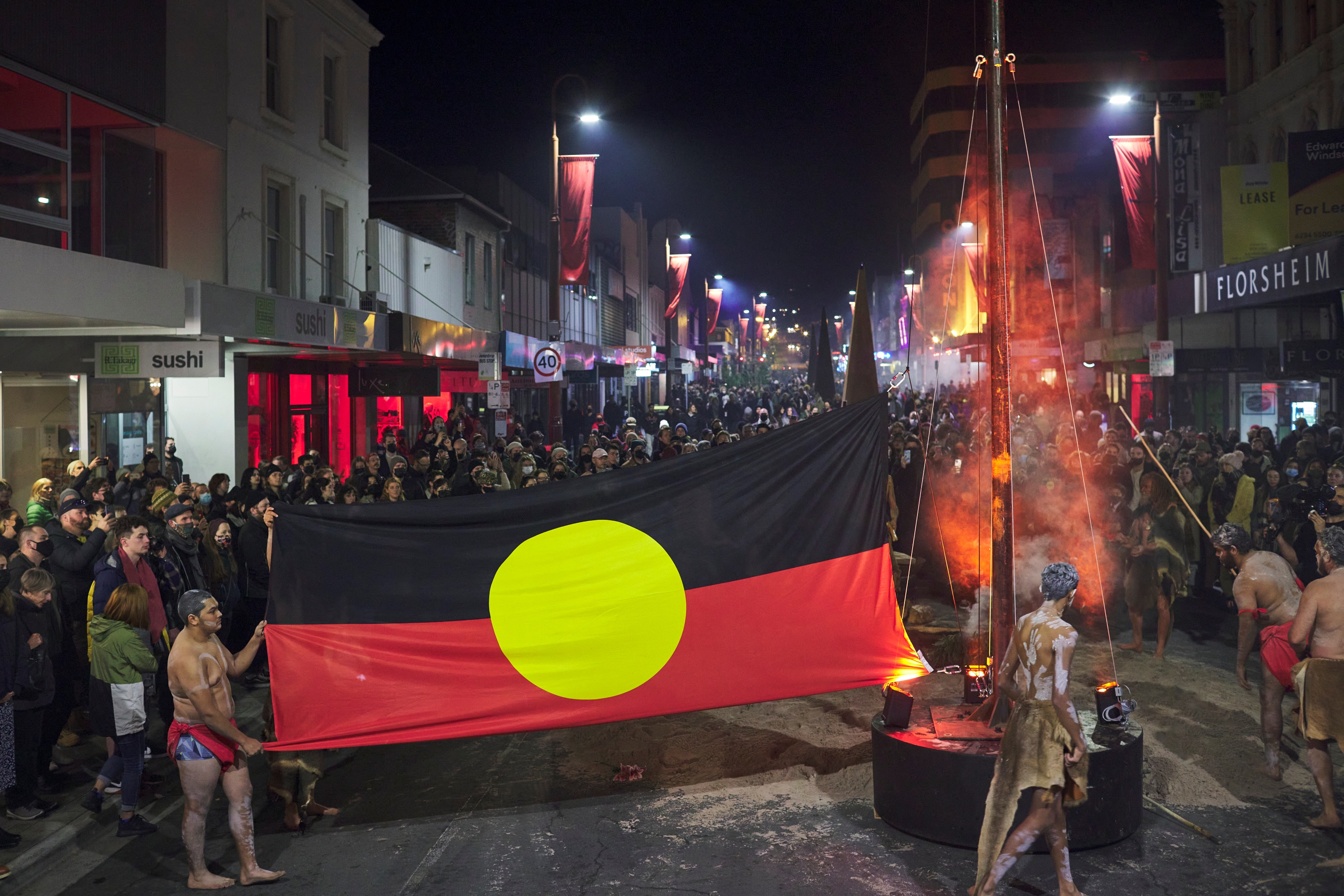 霍巴特街上，一名原住民男子举着原住民旗帜站在路中央