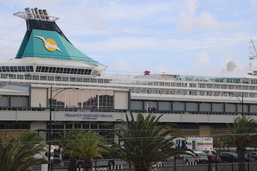 The Artania cruise ship berthed at Fremantle Port with vehicles including a WA Police incident control van parked on the dock.