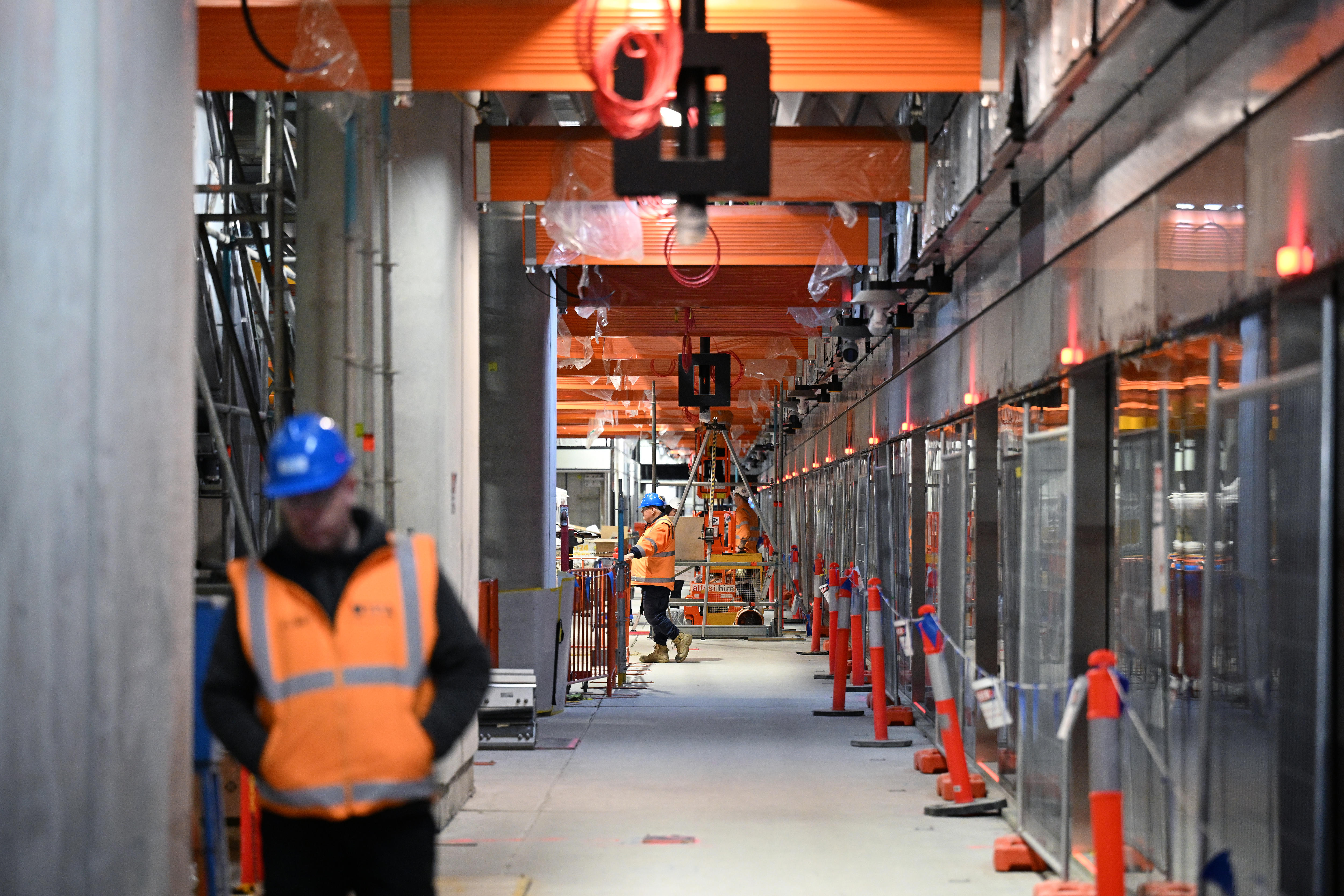 Construction workers stand along a train platform. 