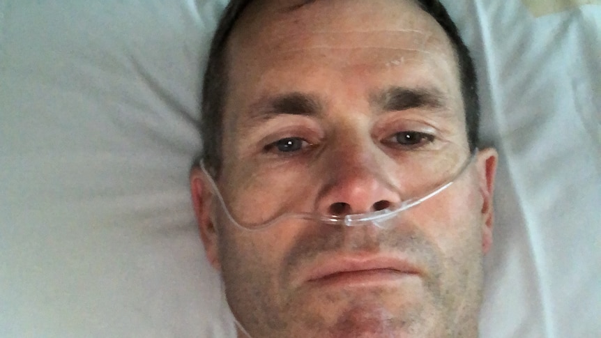 A man on a hospital bed an oxygen tube placed under his nose.