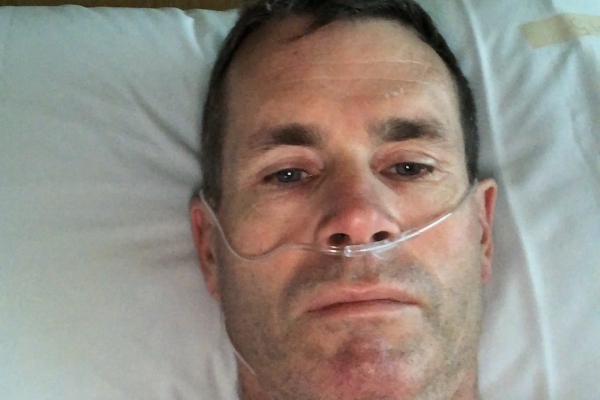 A man on a hospital bed with an oxygen tube placed under his nose.