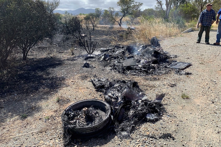 Charred remains of a solar car burned on the side of a road