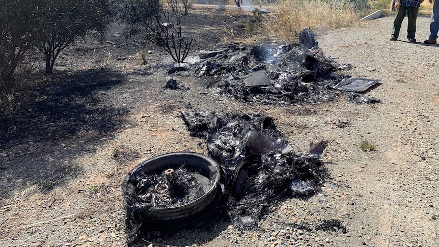 Charred remains of a solar car burned on the side of a road