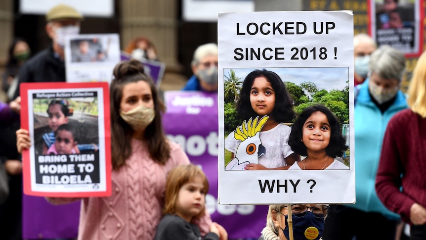 People hold up placards at a rally to support the Biloela Tamil family