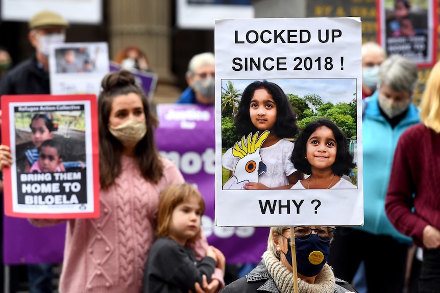 People hold up placards at a rally to support the Biloela Tamil family