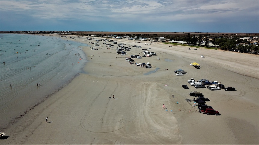 A beach with lots of vehicles parked on it. 