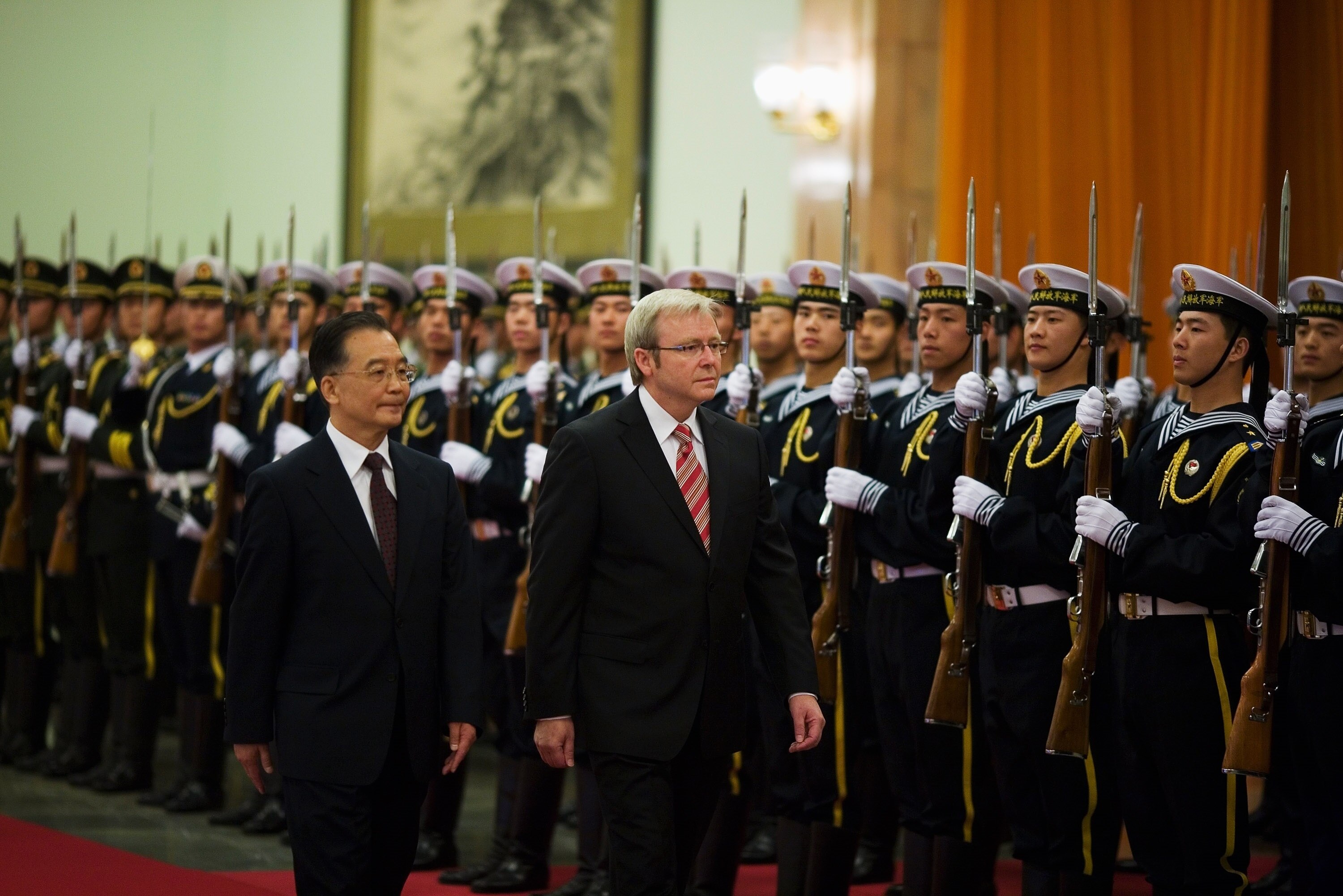 Kevin Rudd walks past lines and lines of Chinese soldiers holding guns.