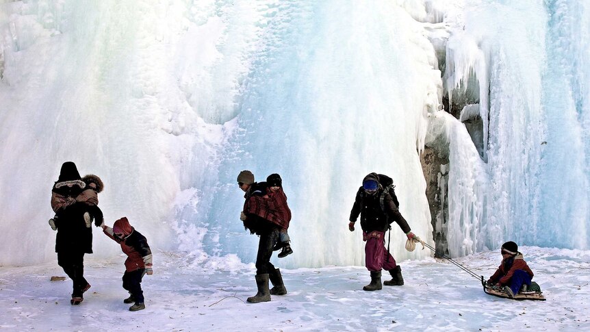 Adults guide children carefully along snow and ice of the Chadar trek