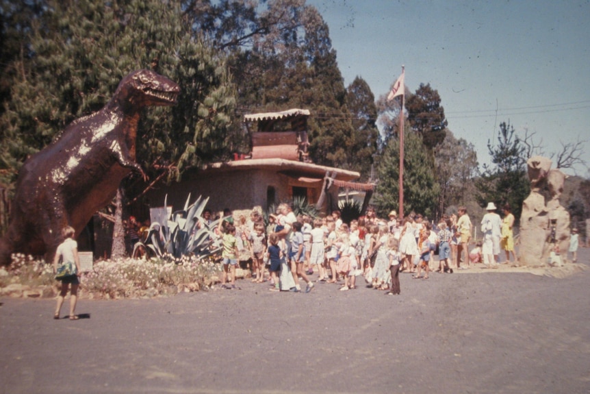 a giant dinosaur at a theme park entrance su