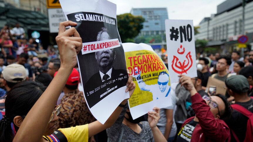 Demonstrators hold placards during a protest against Malaysia's newly sworn in prime minister.