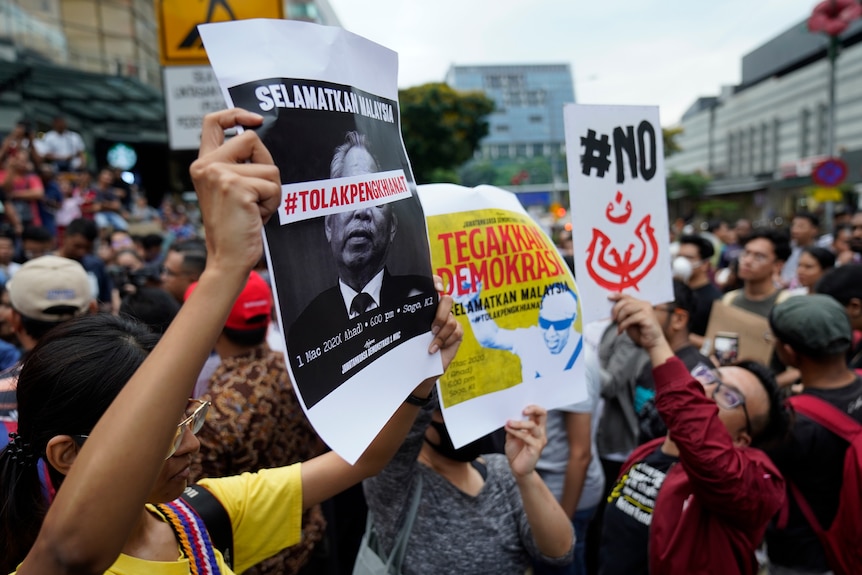 Demonstrators hold placards during a protest against Malaysia's newly sworn in prime minister.