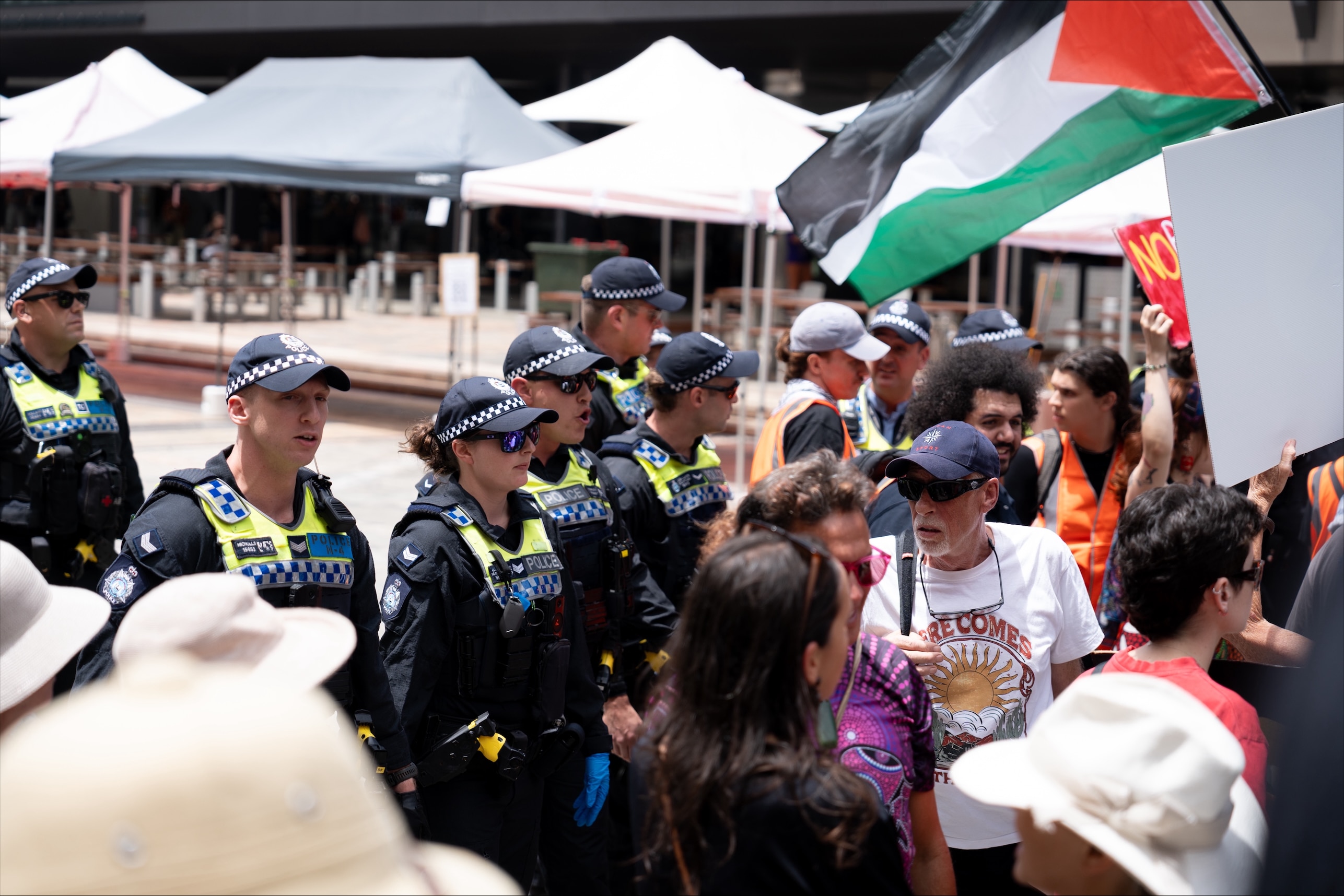 Vários policiais afastam uma multidão em um espaço público