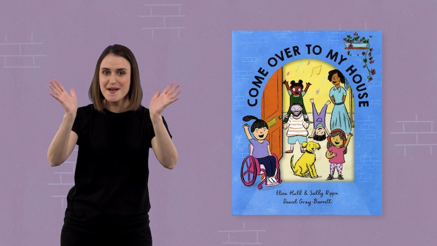 Auslan presenter Julia Murphy stands beside image of book called 'Come Over to My House'