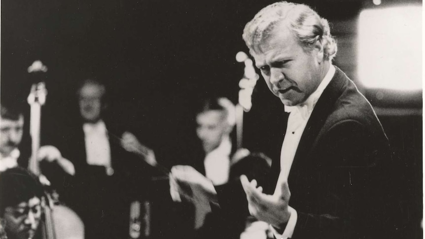Conductor Vladimir Verbitsky gestures towards the camera in rehearsal with orchestra