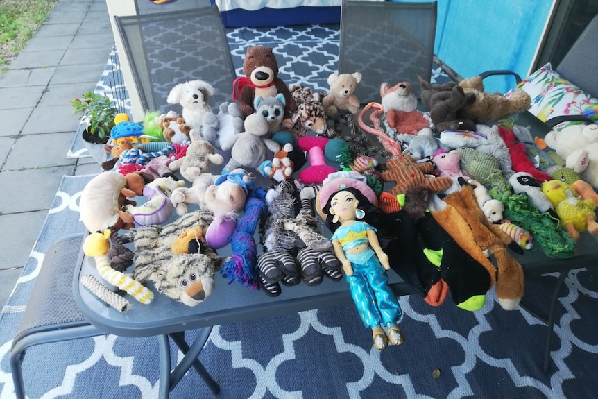 An outdoor table covered in soft toys of all different sizes and shapes