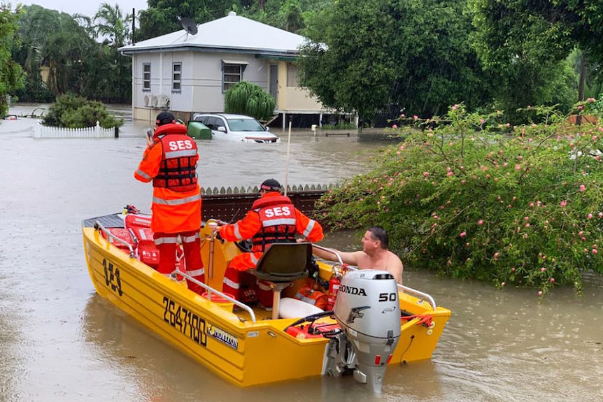 The SES rescuing a man from his flooded home in Townsville