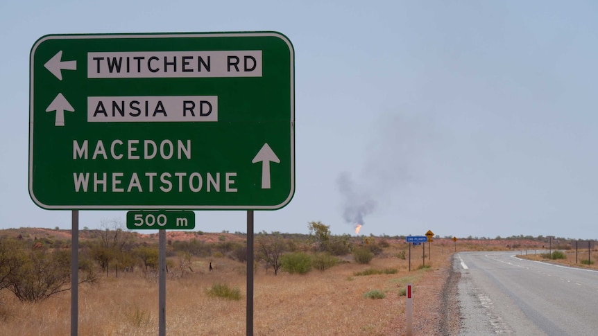 A road sign on the way into the WA town of Onslow with a gas flare in the background