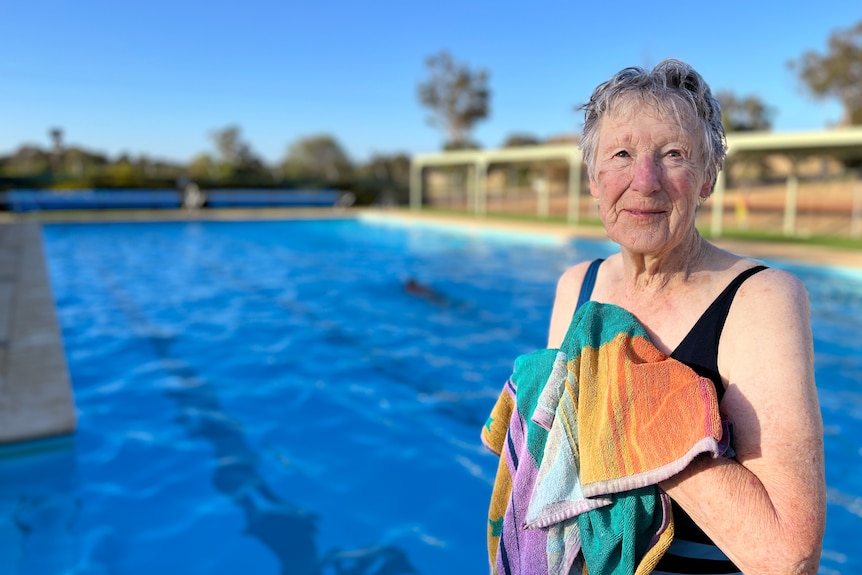 a woman stands in front of a pool