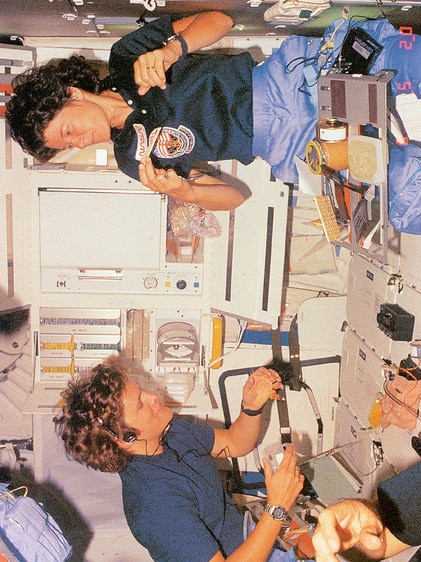 Astronauts Sally Ride (top) and Kathy Sullivan eat together on Ride's second spaceflight.