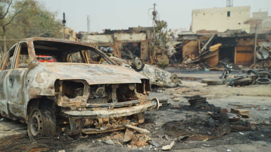 A burnt out car is seen amid the ruins following a riot.