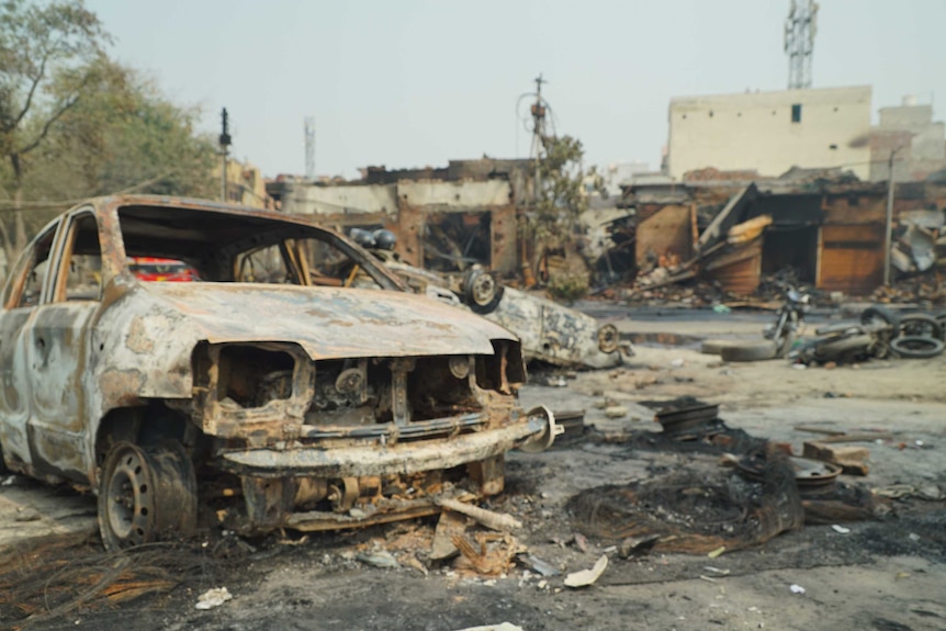 A burnt out car is seen amid the ruins following a riot.