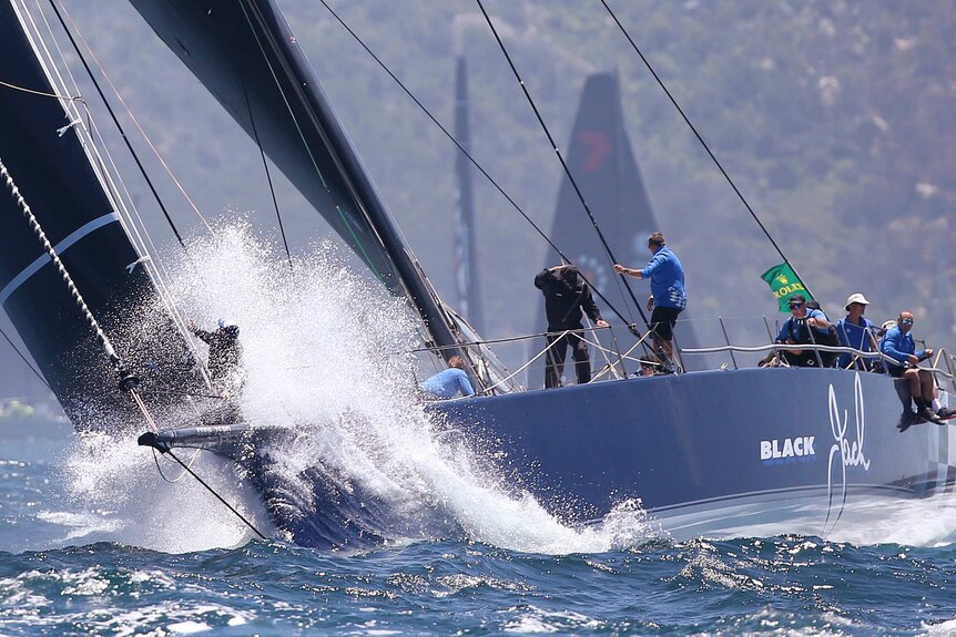 The bowman of Black Jack is sprayed with water early in the 2018 Sydney to Hobart.