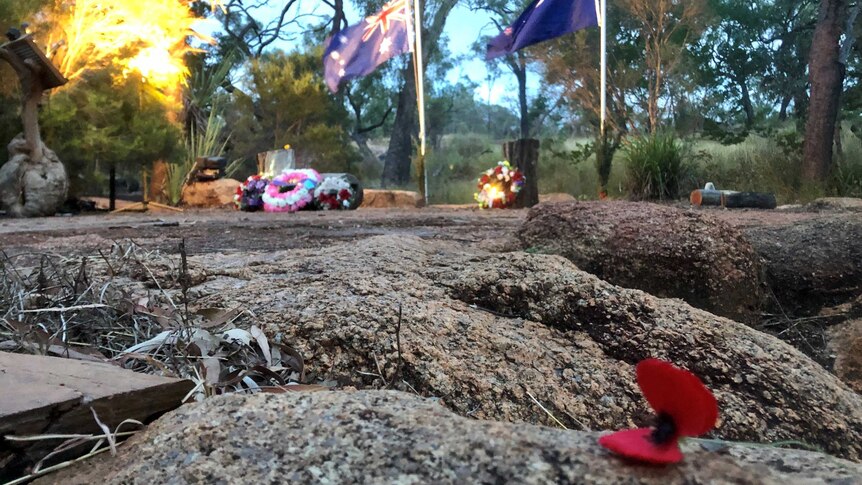 Australian and New Zealand flags are at half mast behind a natural stage of basalt rock where ANZAC Day wreaths are laid.